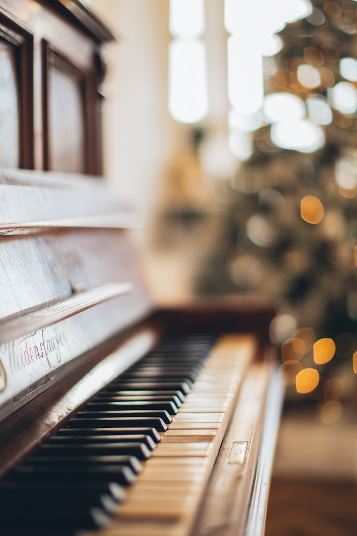 Elegant piano keys in a warm, festive setting with soft bokeh lights.